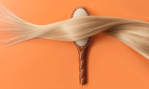 A hair brush has a twisted blonde lock of hair resting over it