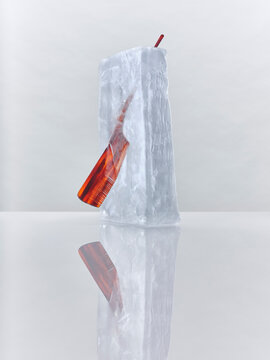 A comb frozen in a block of ice against a white background 