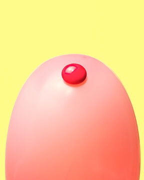 Pink balloon and  red button arranged to look like a finger prick test