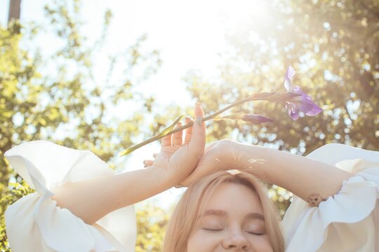 Half face dreamy woman with iris flower in sunlight
