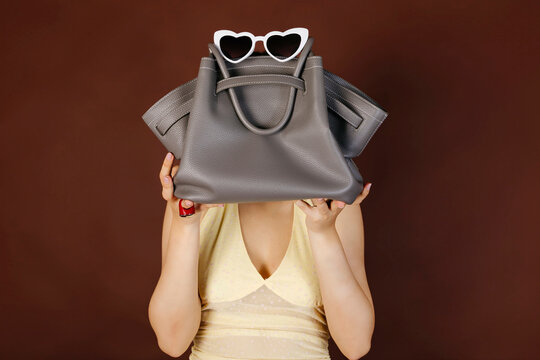 Person holding handbag with sunglasses covering head