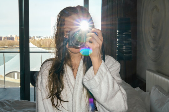 Woman taking mirror self portrait with camera and flash in hotel room.