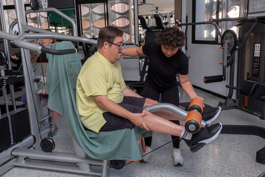 Young person performing adapted training in gym with personal trainer