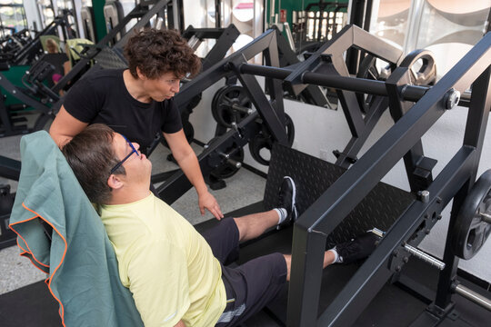 Person performing adapted training in gym with personal trainer