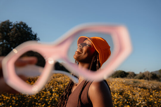 Woman Smiling in a Flower Field Seen Through Glasses During Daylight