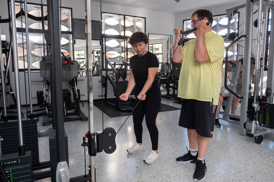 Person performing adapted training in gym with personal trainer