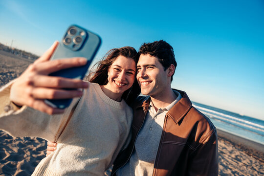 Happy couple taking selfie on beach