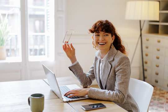 Redhead woman working on laptop smiling in office