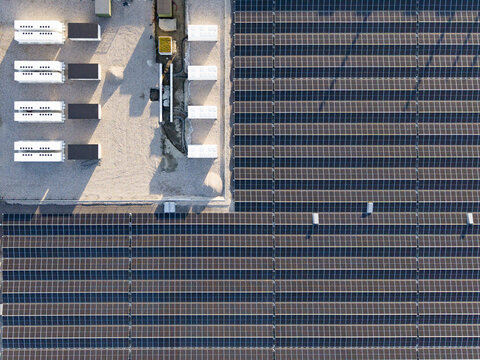 Aerial view of a large solar farm with rows of photovoltaic panels and energy storage containers in Middenmeer, North Holland, Netherlands.