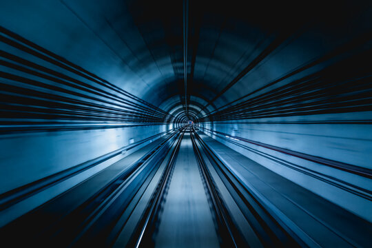 An empty, curved subway tunnel with parallel tracks, captured with motion blur to emphasize speed and perspective depth.
