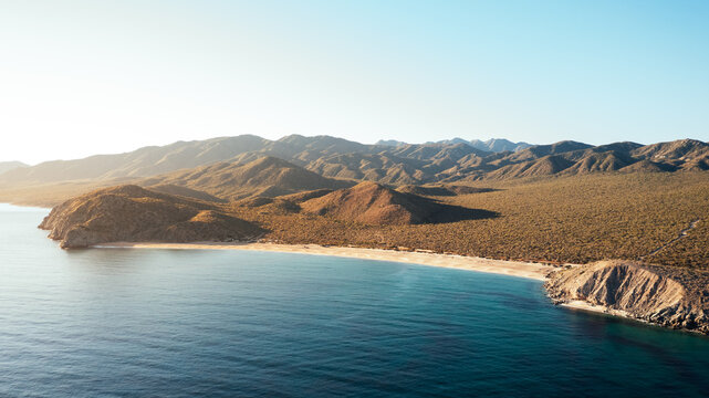 aerial view of desert coastline with turquoise water and arid mo