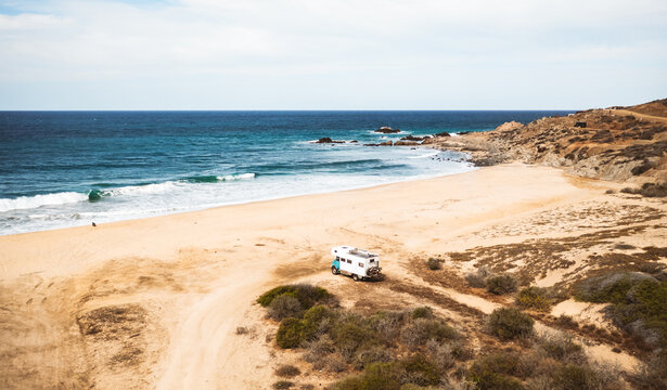 aerial view of truck camper parked on sandy coastal road above t