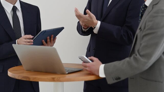 ノートパソコンとタブレットを使って打ち合わせを行う30代と50代の日本人ビジネスマン