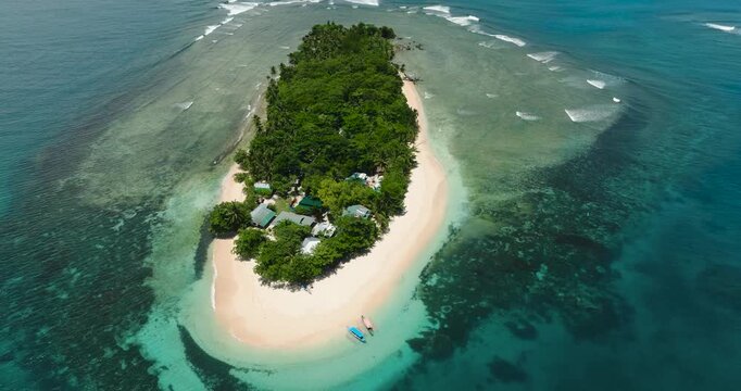 Tropical island surrounded by white sandy beach. Turquoise water and corals on the beach. San Victor Island. Mindanao, Philippines.