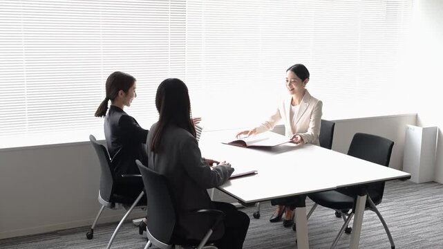 会議室で歩きながら打ち合わせを行う20代から40代の日本人ビジネスパーソン3人