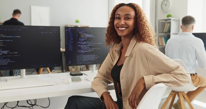 Smiling woman developer programmer in office coding. She works at a computer workstation with code, showing technology skills in a bright office. Clear concept of professional innovation.
