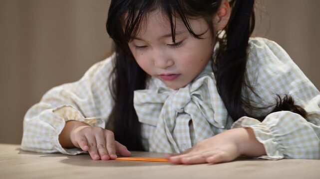 折り紙で遊ぶ6歳の日本人の女の子