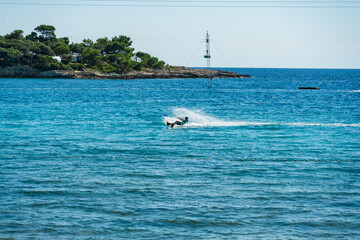 Naklejka premium Wakeboarder riding across the sea at a cable wake park on a sunny day