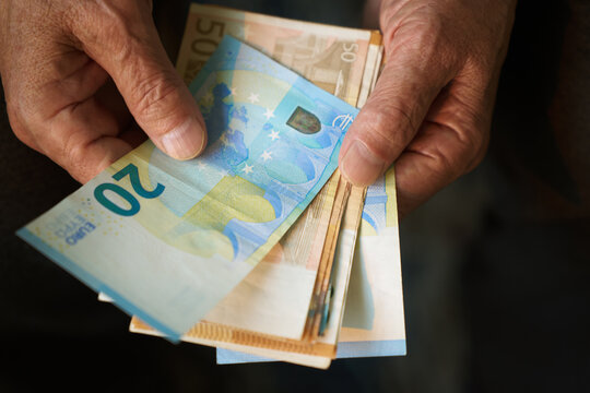 Elderly hands holding euro bills showcasing aging