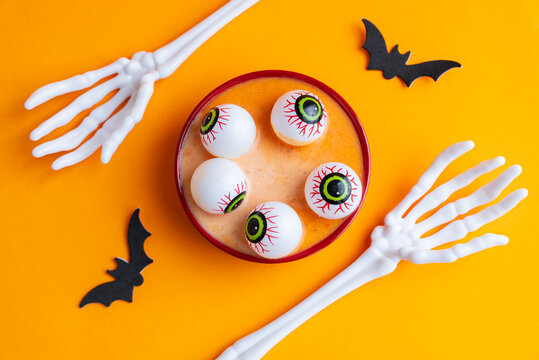Halloween pumpkin soup with funny eyeballs and skeleton