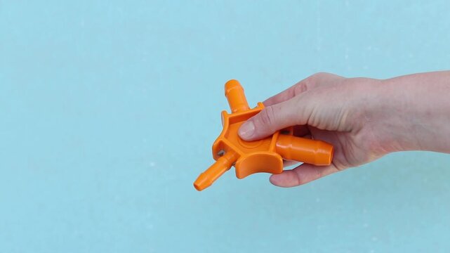 Close-up of a woman's hand with a plumbing tool for calibrating plastic pipes. Manual calibrator for metal-plastic pipes (16-20-25 mm) with beveling knives. Orange plastic calibrator of three-beam des