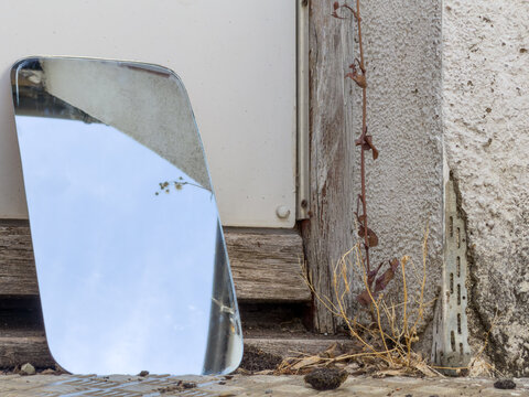 mirror resting against a weathered worn wooden door on a metal floor 