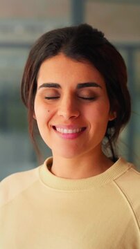 Vertical portrait of beautiful young hispanic business woman, freelance entrepreneur smiling at camera. Latin or eastern middle age female student standing in casual clothes in office. Closeup shot