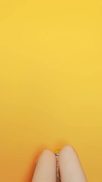 Female legs in funny socks with fried eggs pattern on yellow background. Creative vertical video of woman feet doing walking gesture on colorful wall, fun lifestyle and youth fashion concept