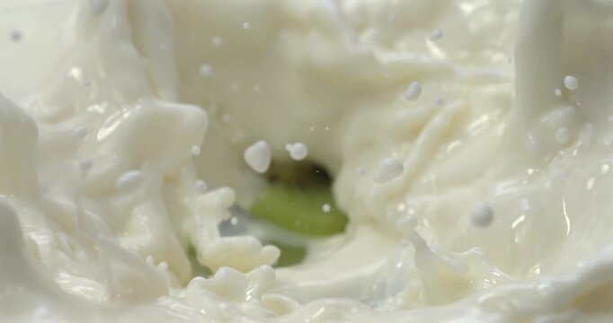 Kiwi slices falling into milk or yogurt with splash in super slow motion 1000 fps
