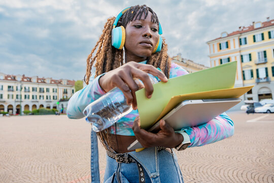Young woman with headphones studying outdoors in city square