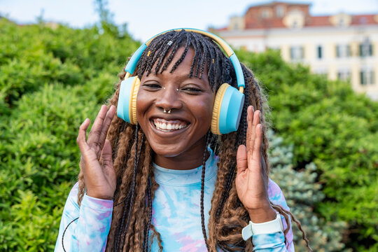 Smiling young woman enjoying music with headphones outdoors
