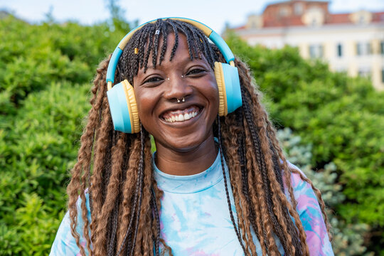 Smiling woman in headphones enjoying music outdoors portrait