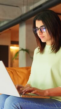 Latin hispanic business woman working on laptop computer in modern coworking office. Indian young freelance professional it specialist, coder, programmer using pc doing online data analysing. Vertical