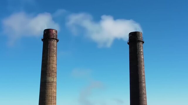 Industrial smokestacks emitting white smoke.