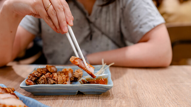 Savoring fried pork with chopsticks in Taipei eatery