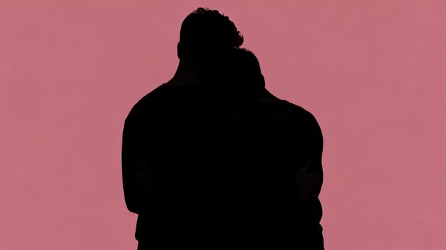 Silhouette of two people embracing against a pink background expressing love and connection