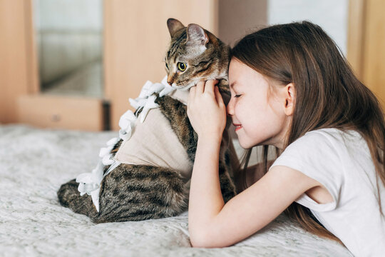 Girl caring for a recovering cat on bed