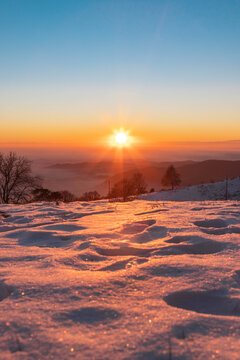 Sole che tramonta tra gli alberi innevati della montagna di Valcava