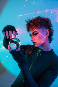 Cyberpunk young woman holding crystal ball in neon light