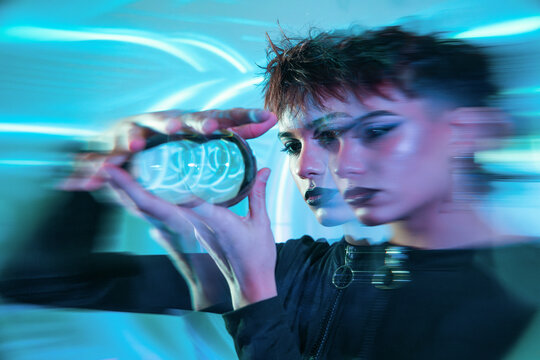 Cyberpunk young woman with holographic device in neon blur