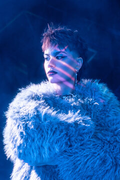 Cyberpunk young woman in neon light with faux fur coat