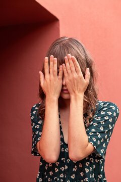 Young woman covering face with hands, mental health concept
