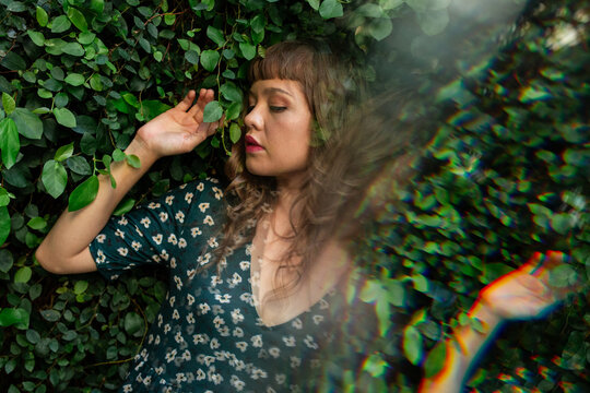 Woman resting among green ivy leaves, calm nature portrait