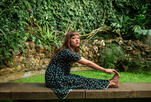 Woman stretching beside pond in lush garden nature setting
