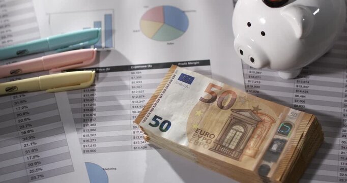 Euro Banknotes and Piggy Bank in Slow Motion on Financial Documents