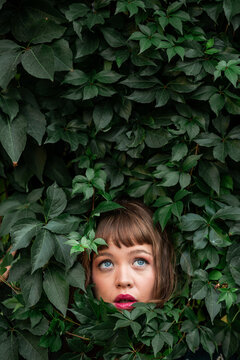 Woman portrait framed by lush green leaves in nature