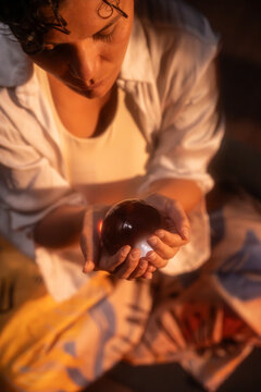 Spiritual Latin woman holding crystal ball at night