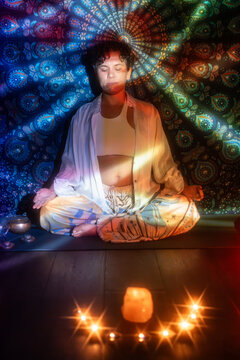 Meditating Latin woman in esoteric candlelit aura light