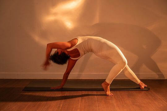 Latin woman practicing yoga backbend pose in warm light