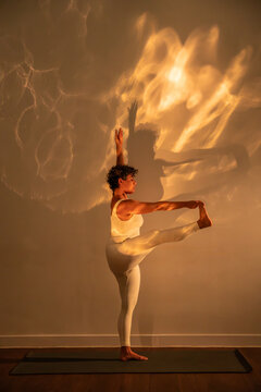 Latin woman practicing yoga with dramatic wall shadow